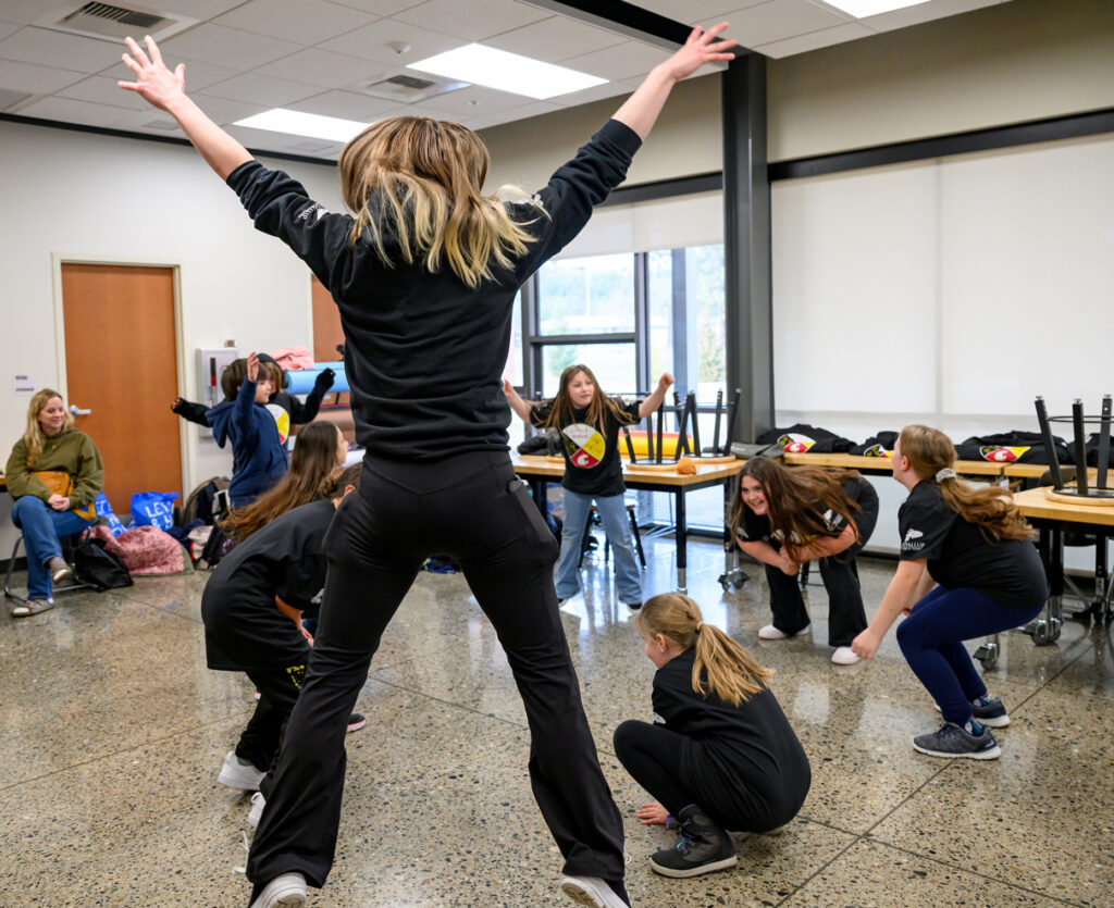 A WSU student leaps into the air as they lead several Little Bird students in a group exercise activity.