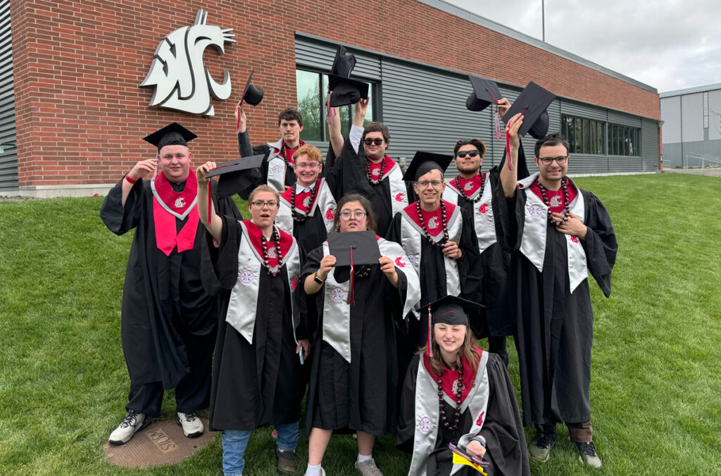 WSU ROAR students celebrating commencement while wearing caps and gowns for a group photo.