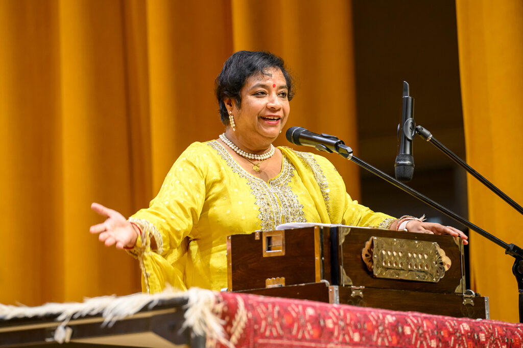 Susmita Bose standing on stage during a North Indian classical music and dance concert.