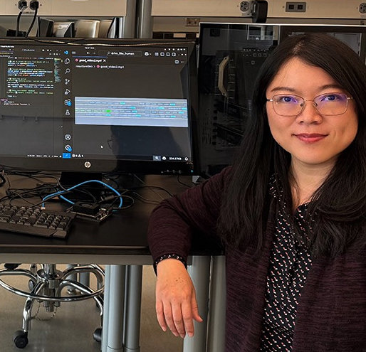 Xinghui Zhao sitting next to a computer in a lab.