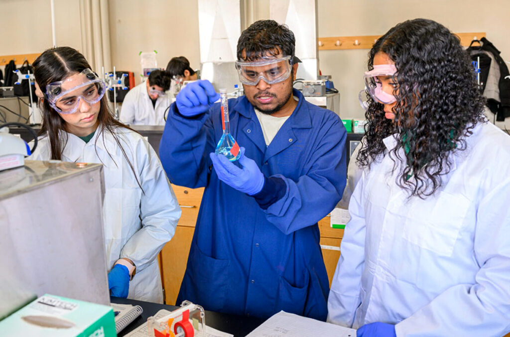Three undergraduate students working on experiments in a chemistry lab.