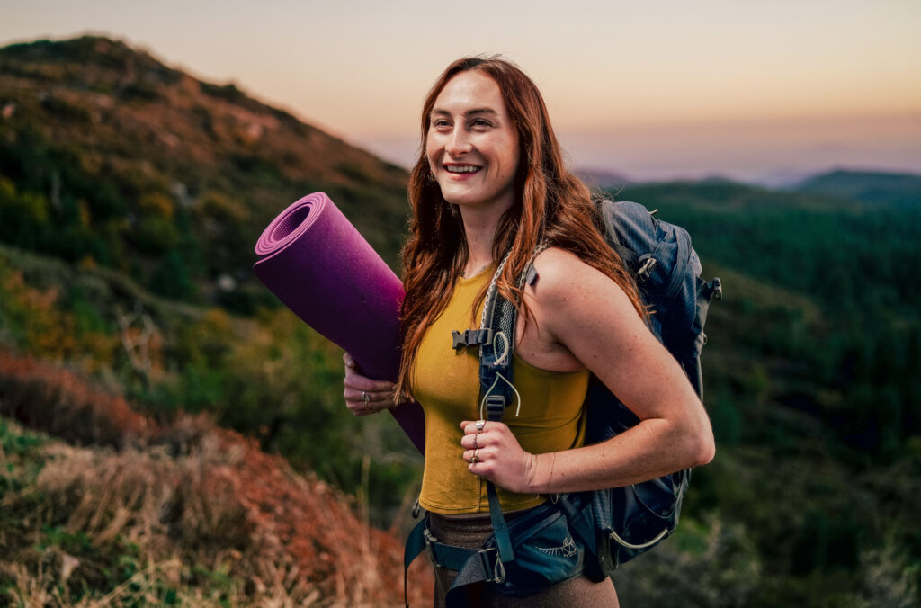 Ella Spillane walking up a hill with a yoga mat and backpack on Catalina Island in California.