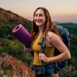 Ella Spillane walking up a hill with a yoga mat and backpack.