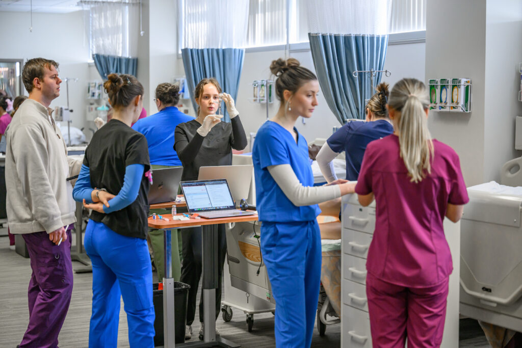 WSU nursing students and faculty practicing injections in a medical classroom.