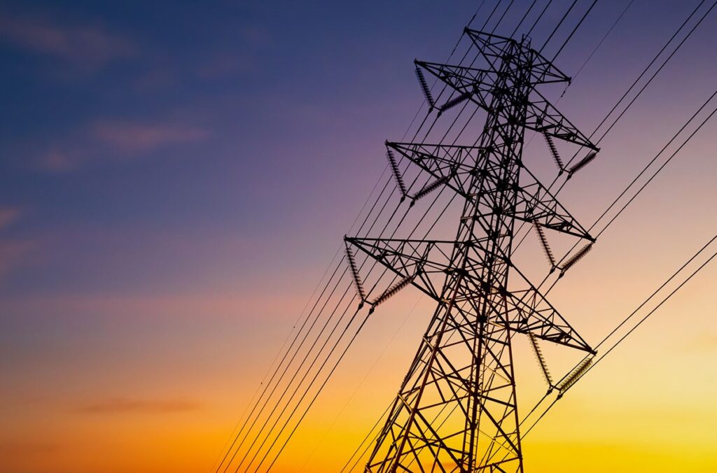 A transmission tower is shown at sunset.