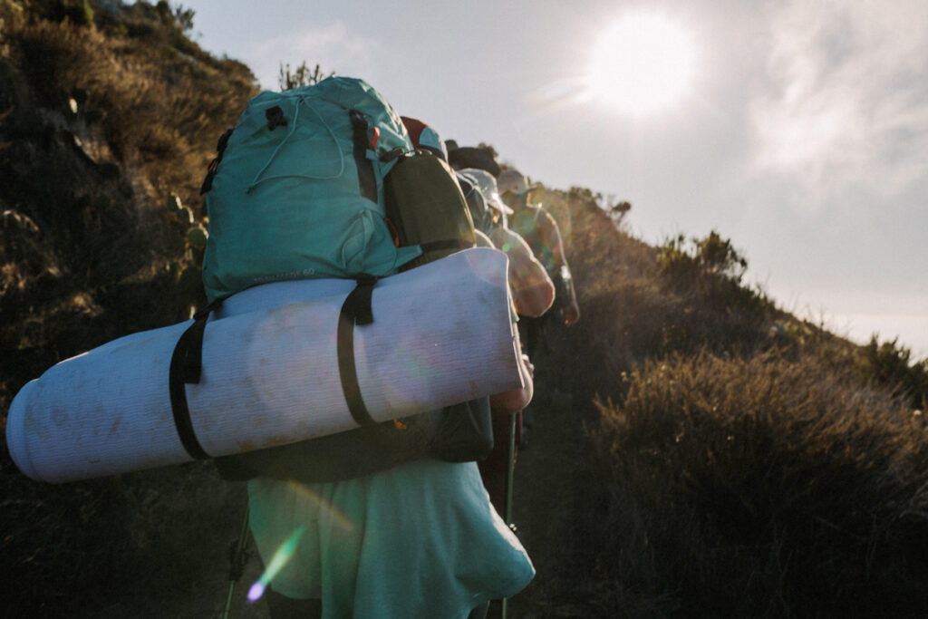 A group of backpackers hiking up a hill.