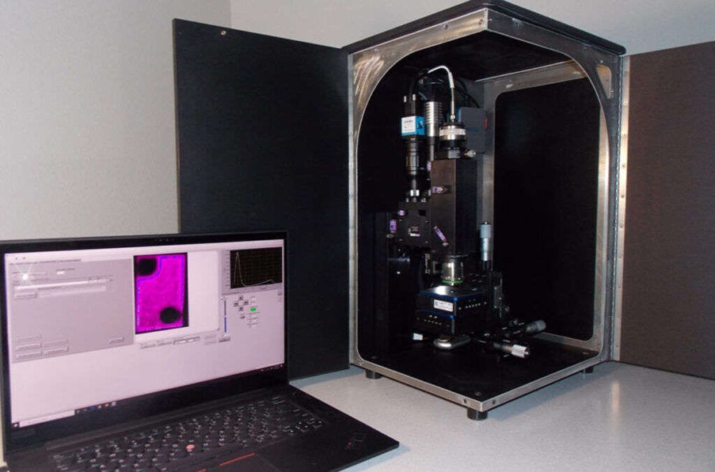 Closeup of Klar Scientific's new microscope design next to a laptop.