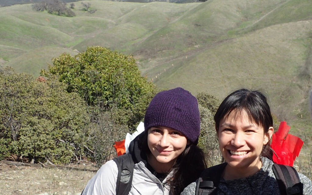 Two researchers pose in the field, where they are gathering rhizobia bacteria.