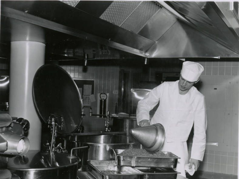 A cook prepares a meal at a stainless steel counter in 1961. 