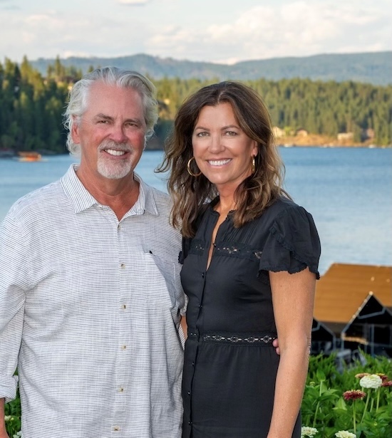 Scott and Lisa Taylor pose for a photo outside in front of a lake. 