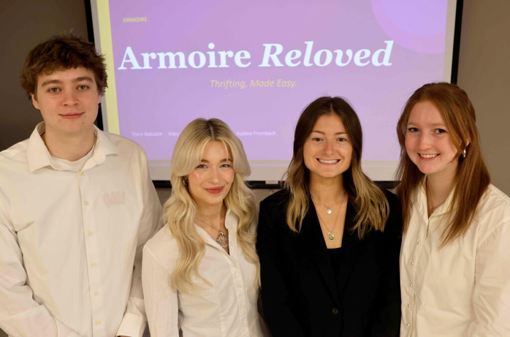 Closeup of Trace Bakulich, Audree Frombach, Aley Matarangas, and Kiley Hill in front of a projector screen.