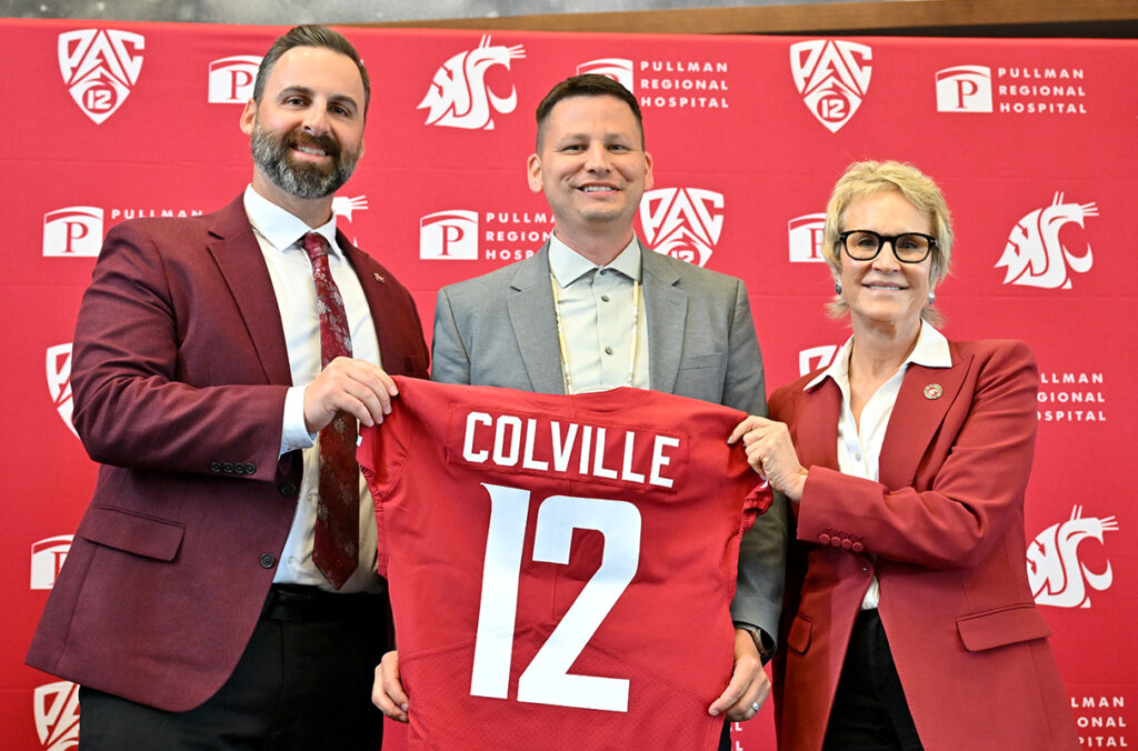 Jon Haarlow and Betsy Cantwell presenting a WSU football jersey with "Colville" on it to Jarred-Michael Erickson.
