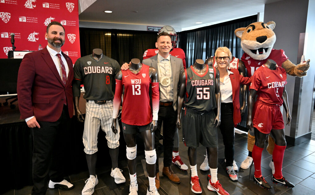 Jon Haarlow, Jarred-Michael Erickson, Betsy Cantwell, and Butch T. Cougar standing with mannequins featuring WSU athletic uniforms with Colville Tribe jersey patches.