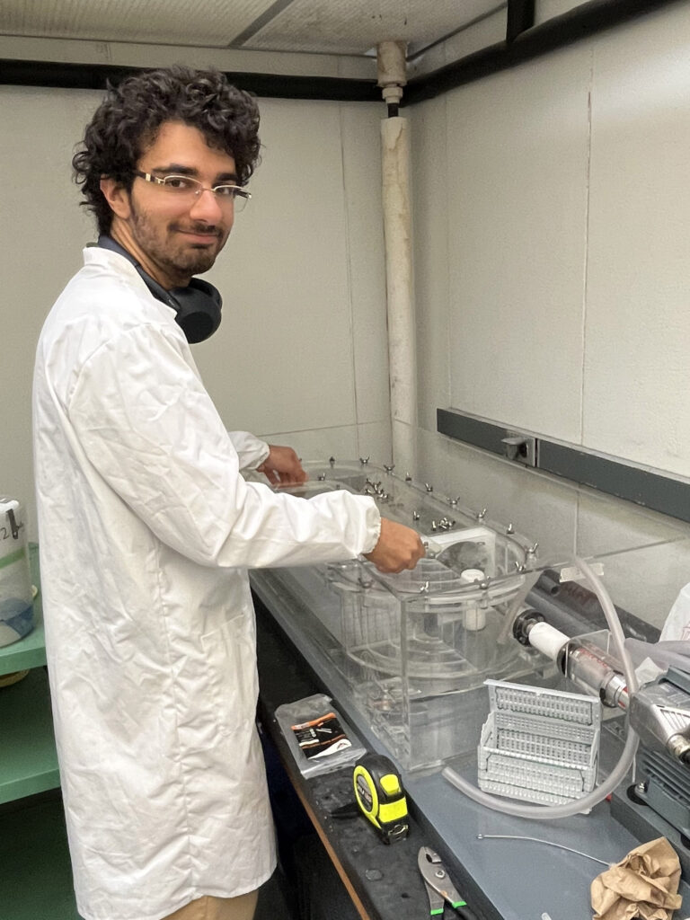 A man in a lab coat prepares a see-through swim chamber for fish.