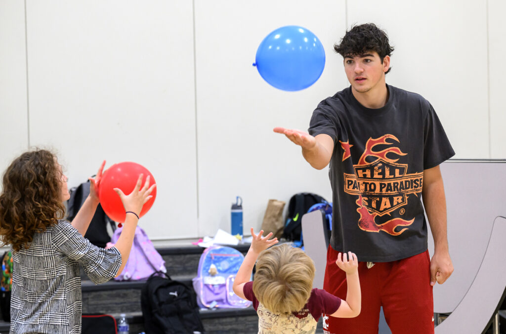 A WSU student-athlete bounces a balloon off his hand as he plays with elementary school children.