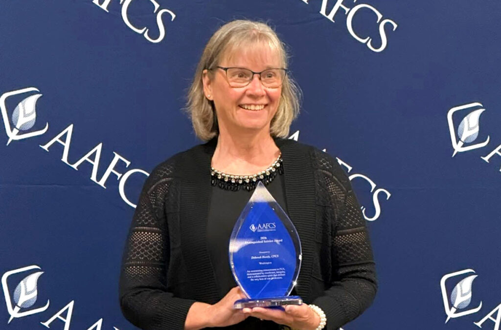 Debbie Handy holding the 2026 AAFCS Distinguished Service Award.