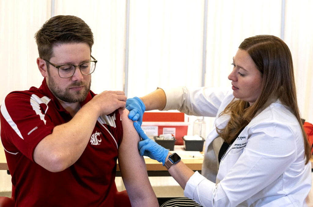 A professor demonstrates the technique for giving an immunization.