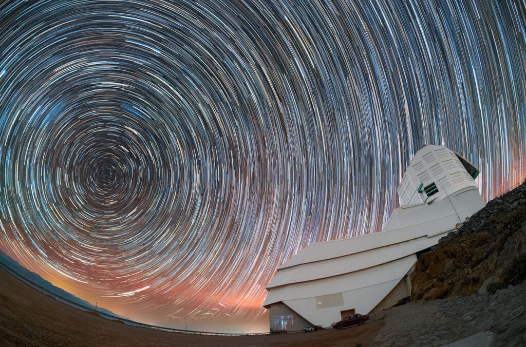 Star trails can be seen circling above the Vera Rubin Observatory in a long exposure image.