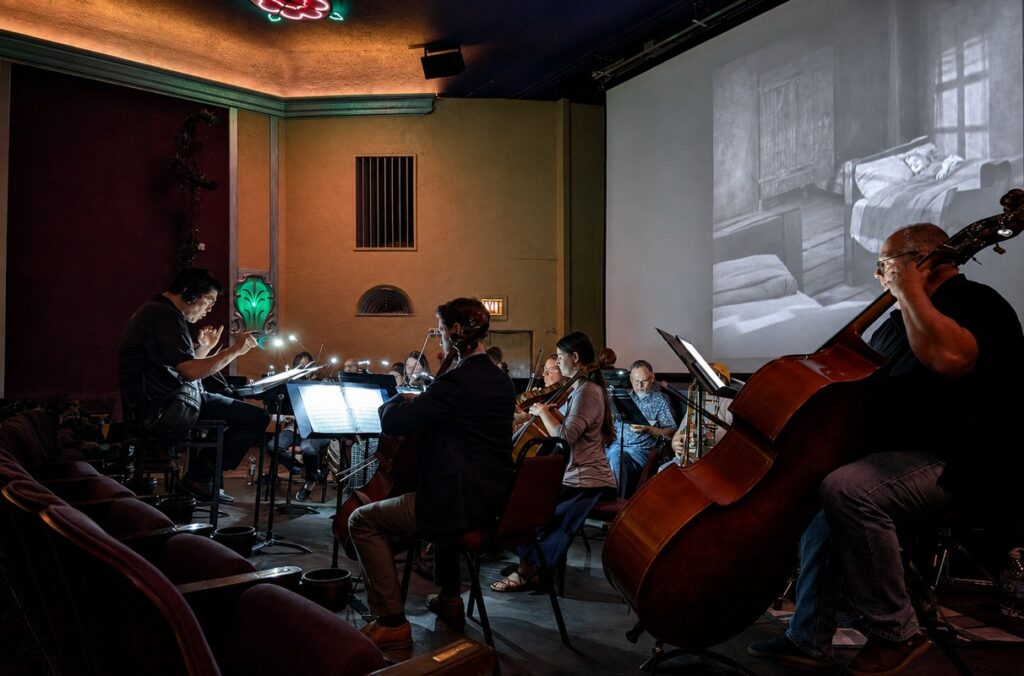 Musicians perform in front of a silent film.
