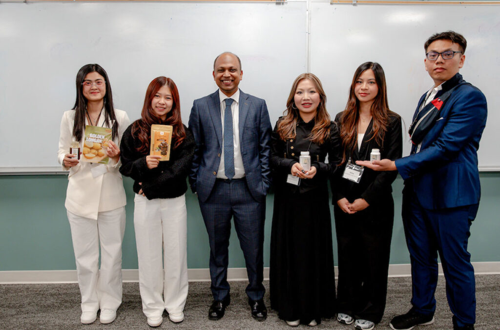 Alt text: Assistant Professor Monirul Islam poses with five CamEd Business School students holding products representing their entrepreneurial venture concepts during a visit to Washington State University's Carson College of Business.