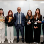 Alt text: Assistant Professor Monirul Islam poses with five CamEd Business School students holding products representing their entrepreneurial venture concepts during a visit to Washington State University's Carson College of Business.