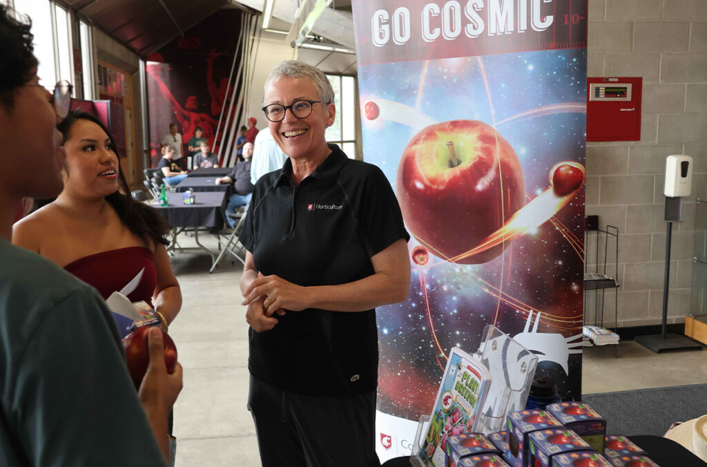 Closeup of Professor Kate Evans handing out apples.
