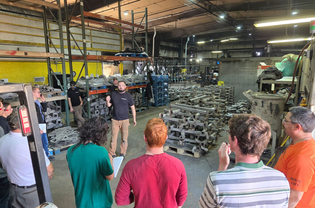 A group of students can be seen touring a manufacturing facility.