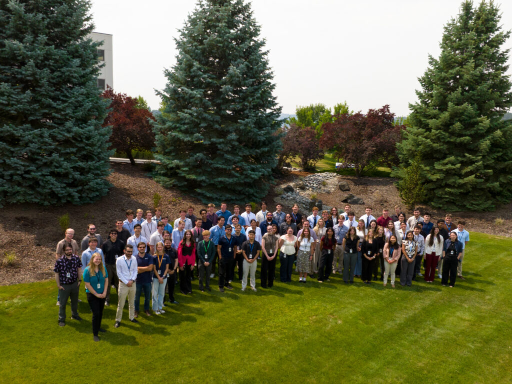 A large group of interns stand in a field for a photo.