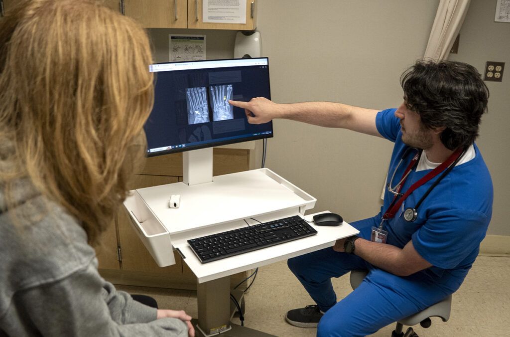 A male medical professional visits with a female patient while pointing at x-rays.