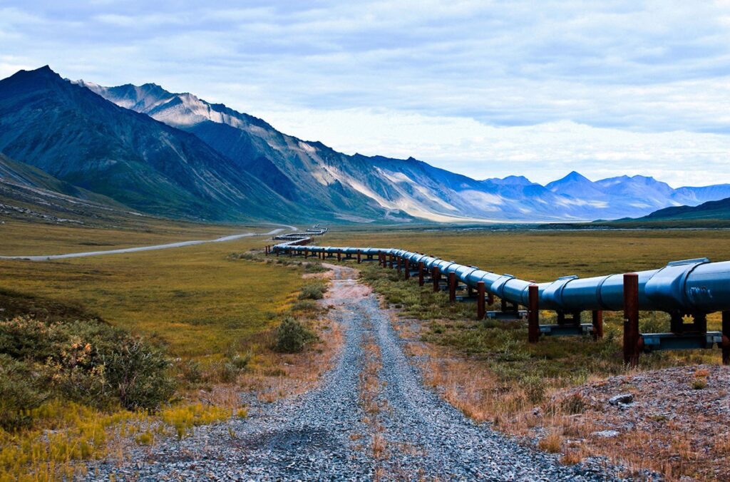 A pipeline runs alongside a gravel road in Alaska.