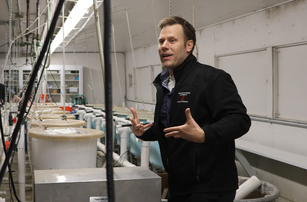 A man talks to a group of visitors in a aquaculture laboratory.