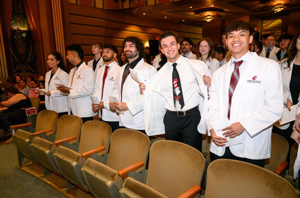 Pharmacy students wear their white coats in a line at the Fox Theater in Spokane.