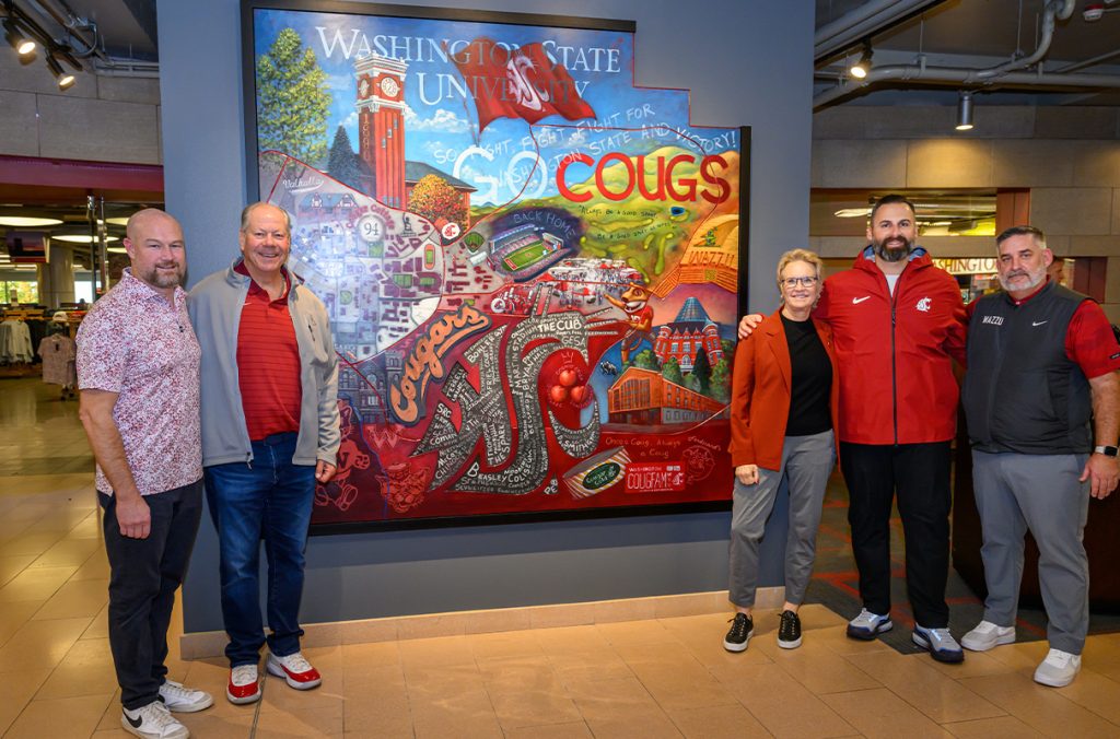 A group of people stand around a new artwork piece depicting the Pullman campus.