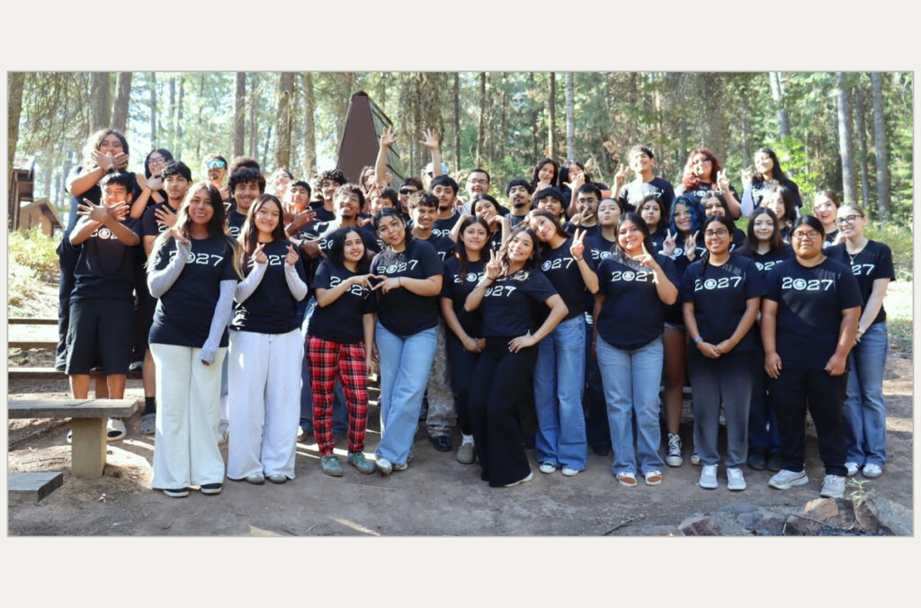 A group of students pose for a picture with their hands raised.