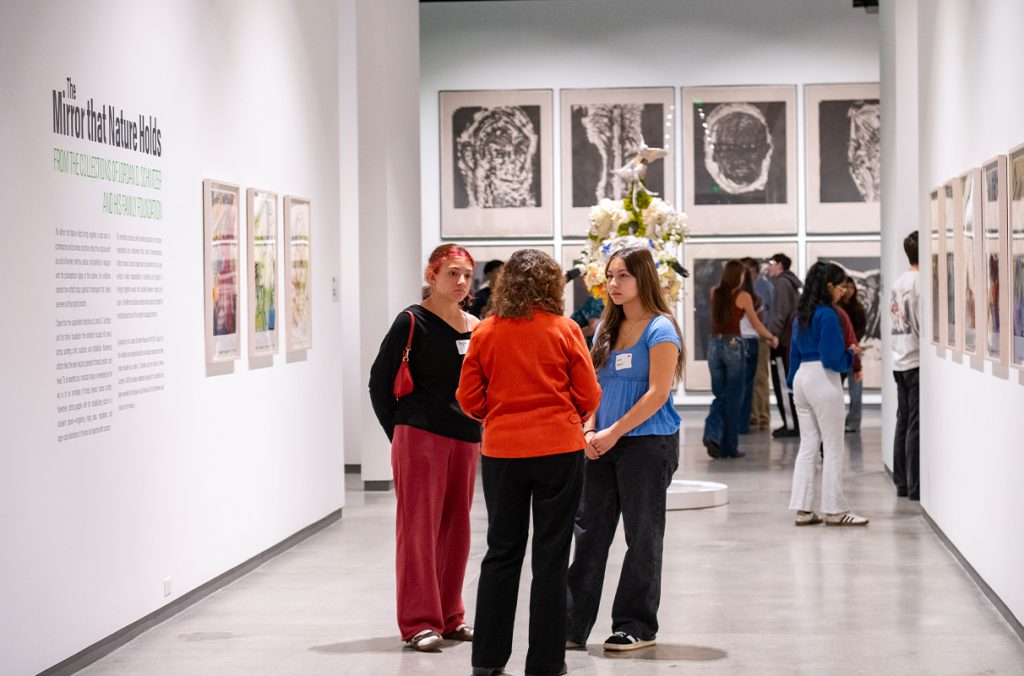 People stand in a hallway looking at art.