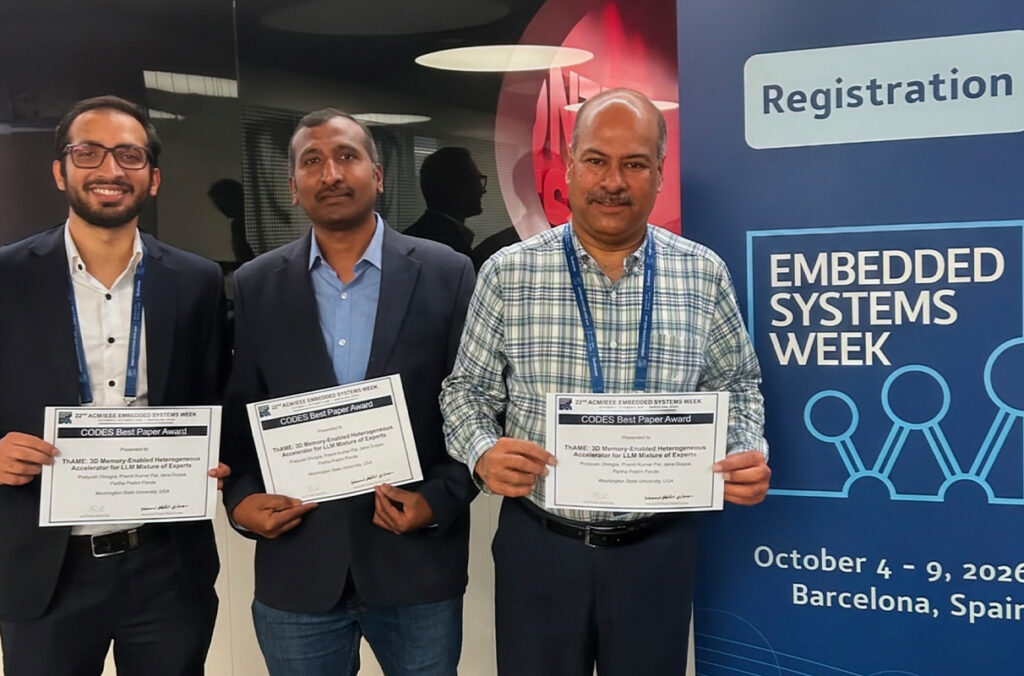 Three men pose for a photo while each holding a white certificate. The text on the awards is not readable. There are standing next to a vertical sign on the left side of the image with text Registration. Embedded Systems Week October 4-9, 2026 Barcelona, Spain.