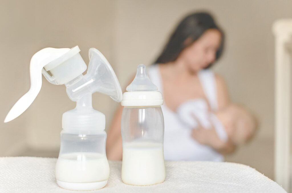 An illustration shows breast milk in bottles while a mother nurses in the background.