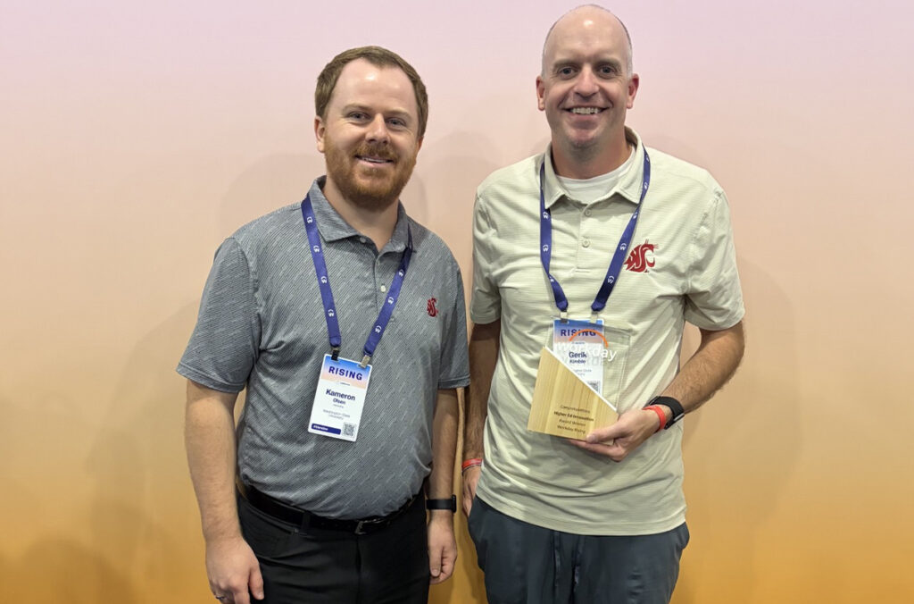 Two men stand next to each other holding an award.
