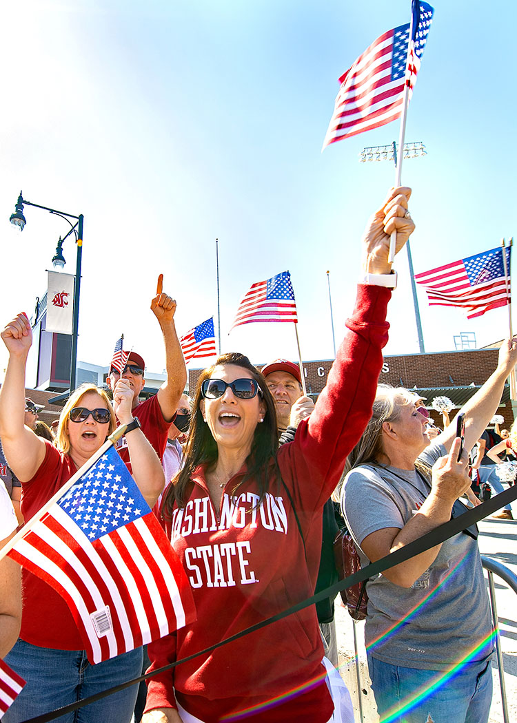 Alumni and Parents wave American Flags in front of the Cougar Pride Statue on WSU's campus in Pullman, WA