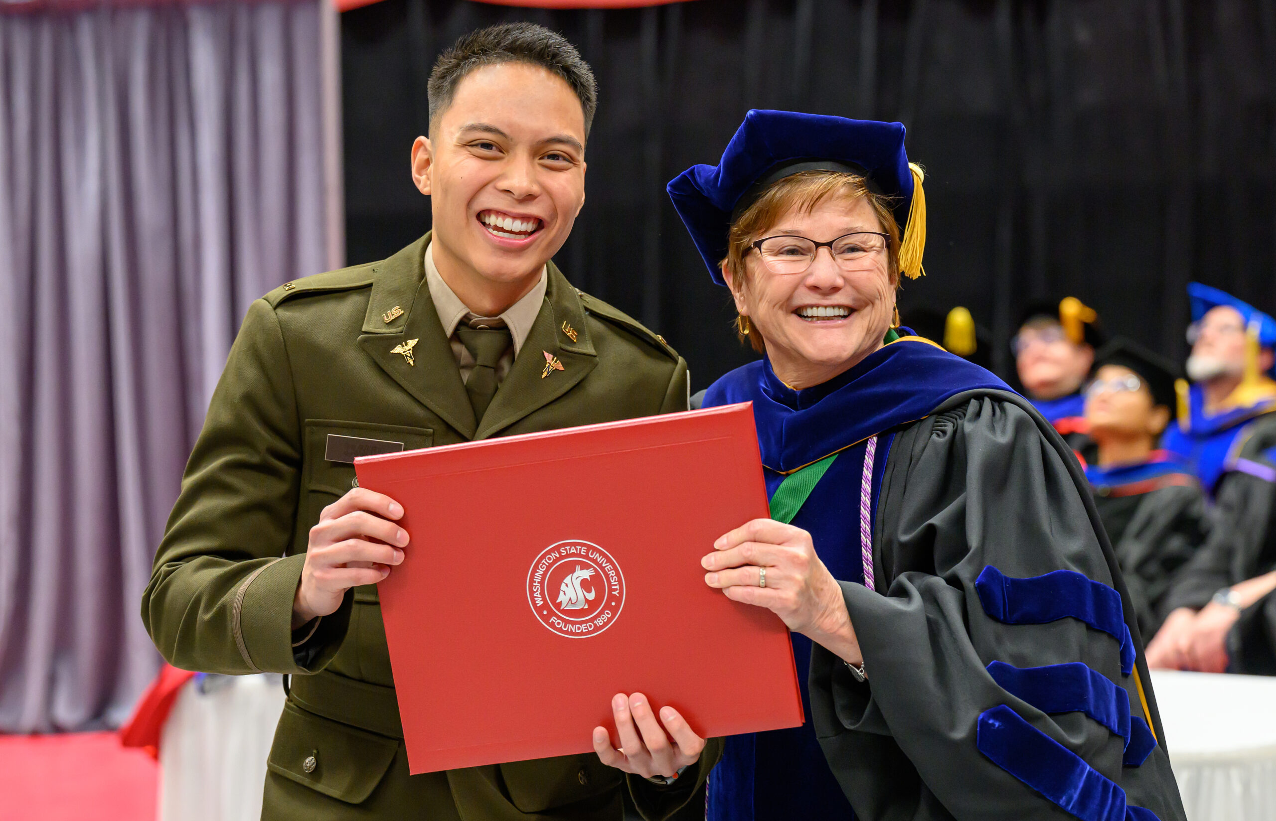 Student proudly holds up their degree at the commencement ceremony at WSU