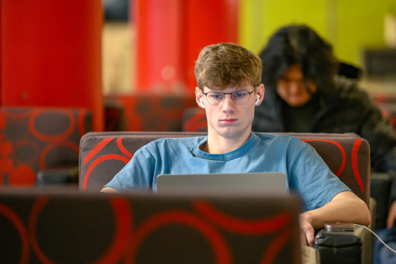 Student sitting in chair looking at laptop