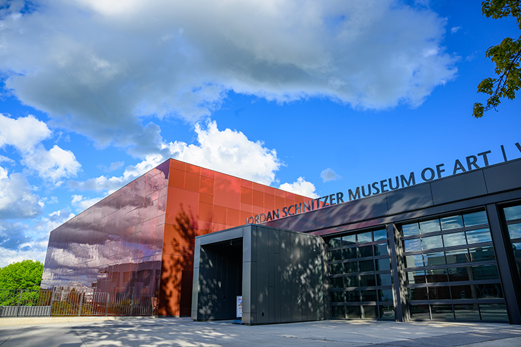 Exterior of the Jordan Schnitzer Museum of Art and the Crimson cube with a beautiful blue sky in the background.