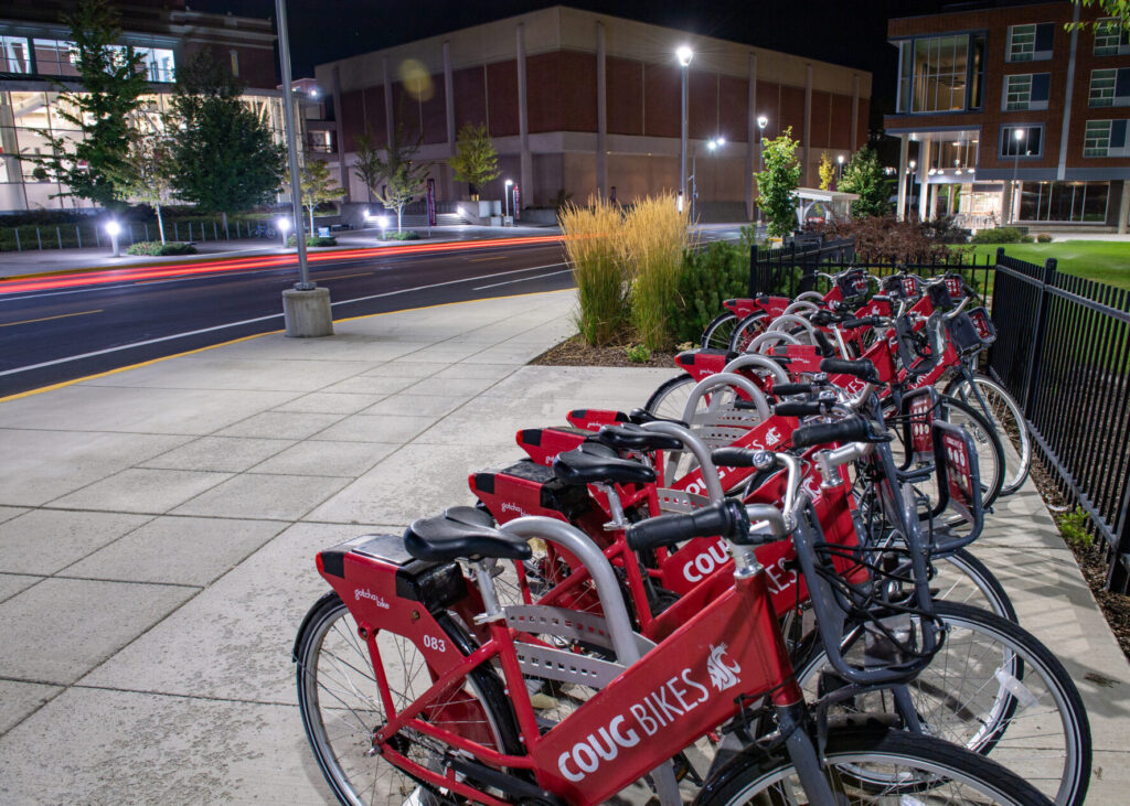 A bike rack filled with Coug Bikes along a WSU Pullman campus street.