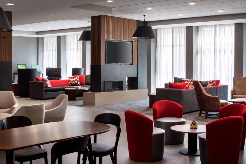 The lobby of a hotel with chairs, tables, and a fireplace.