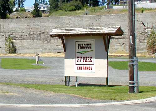 A sign in a parking lot that reads Palouse RV Park entrance.