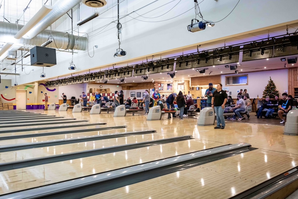 Bowling alley lanes with people bowling.