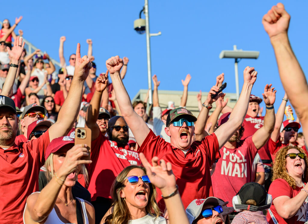 A crowd of cheering fans wearing crimson shirts.
