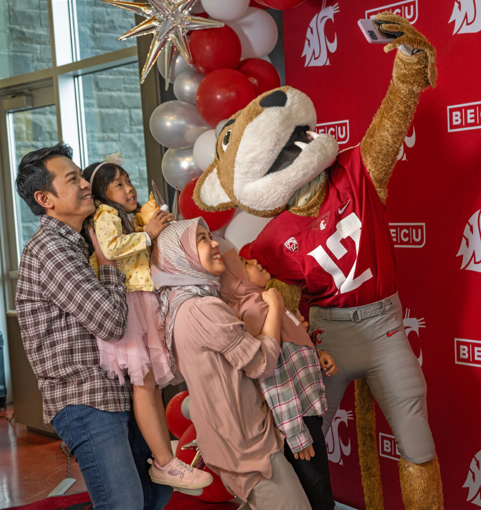 WSU mascot Butch cougar posing for a selfie with a family.