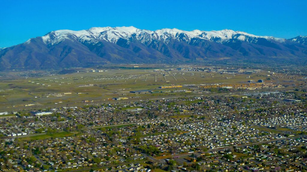 Aerial view of snow-topped mountains, fields, and a sprawling community