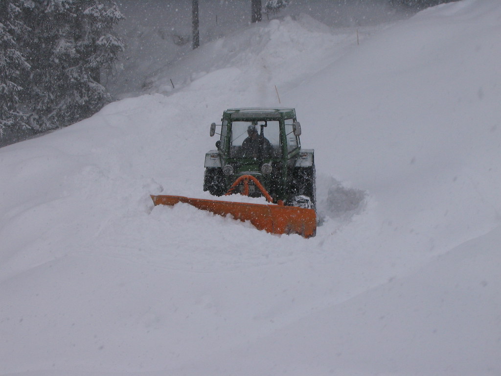 Tractor with a snowplow moving through deep snow